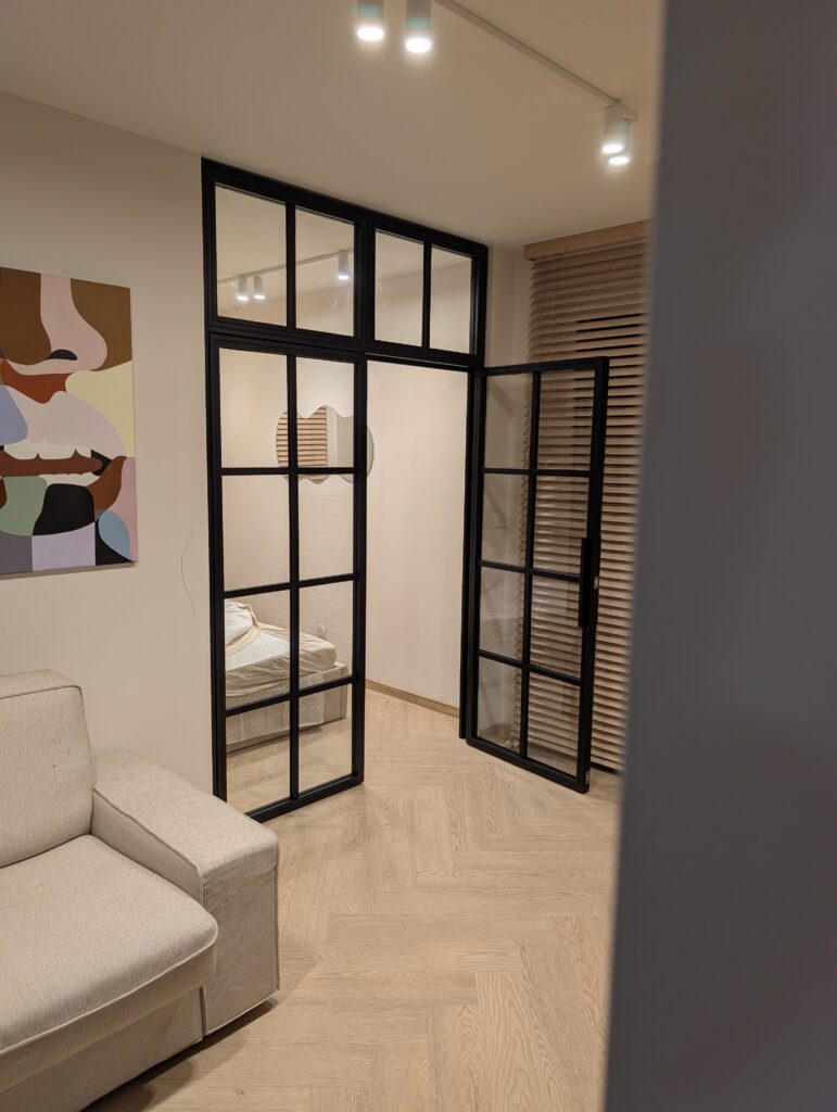 Industrialne drzwi loftowe dwuskrzydłowe z naświetlem bocznym i górnym – czarna przeszklona ścianka stalowa w sypialni Loft Steel Tarnów